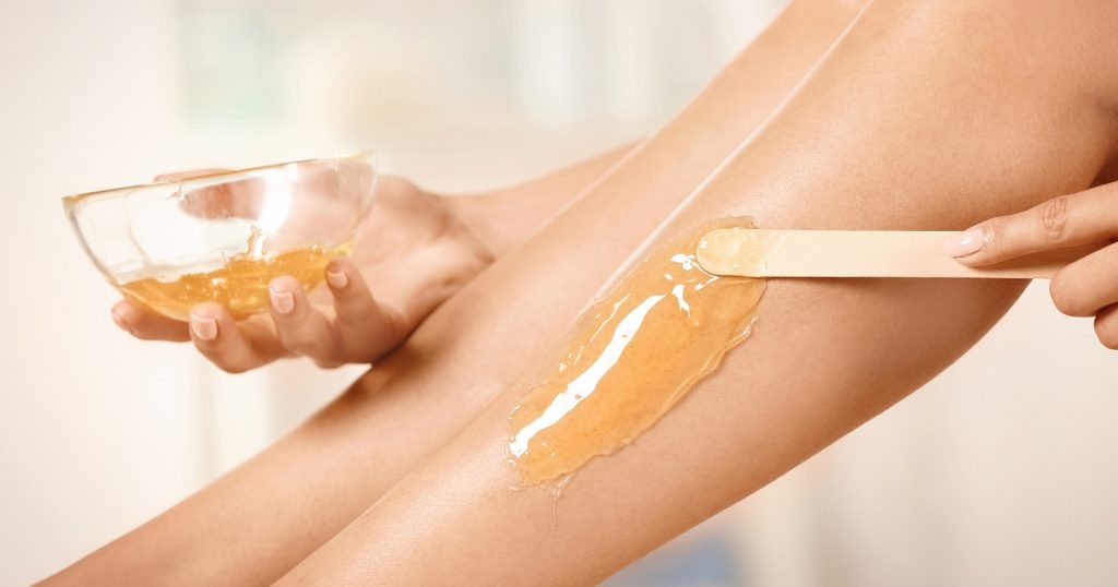 Applying wax to the leg with a spatula before hair removal.