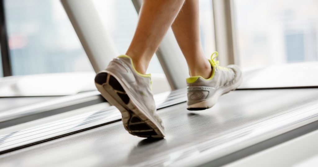 Person walking on a treadmill, a light activity to try when working out after laser hair removal.